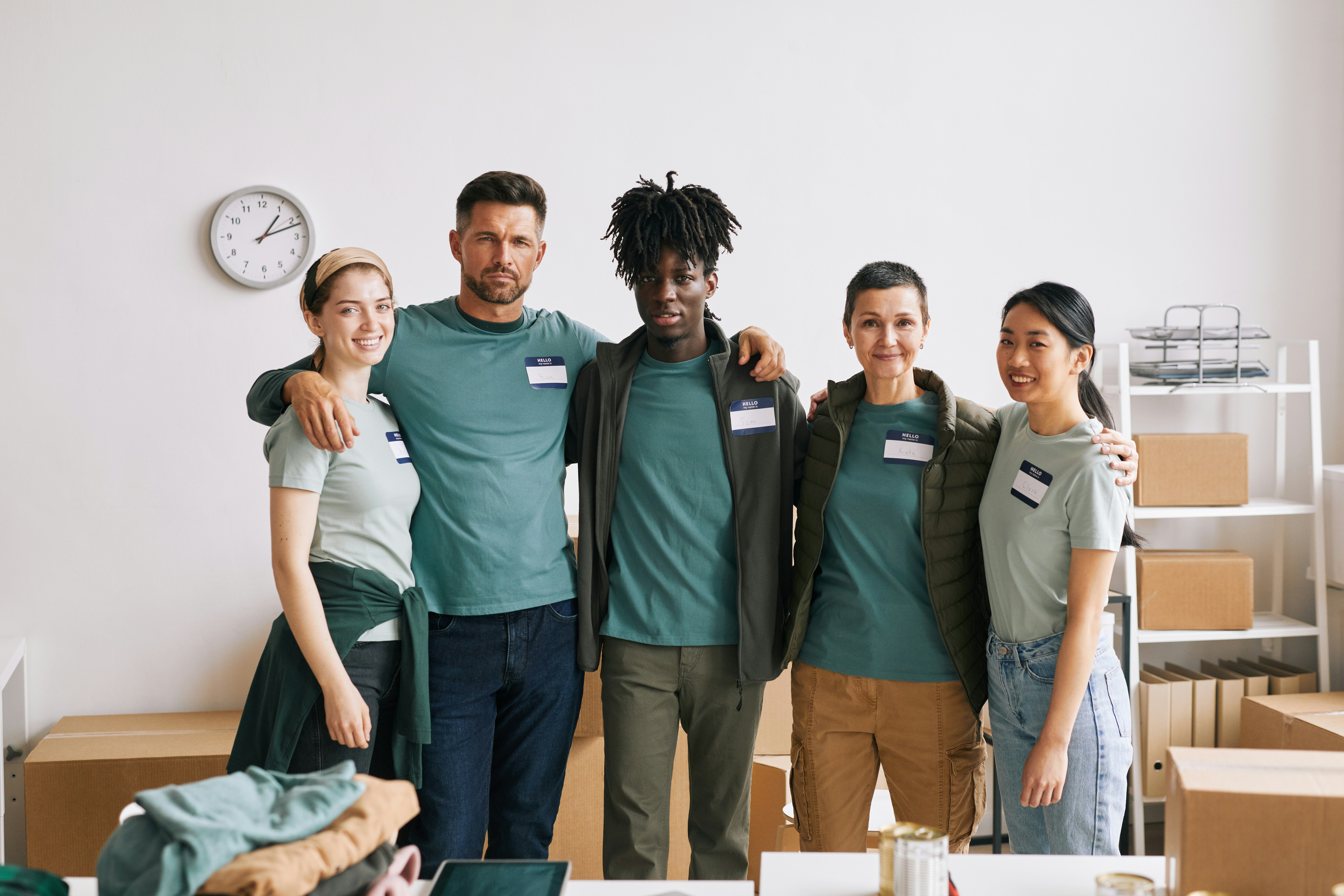 Group of nonprofit staff standing together in a workspace with boxes and clothing donations nearby.