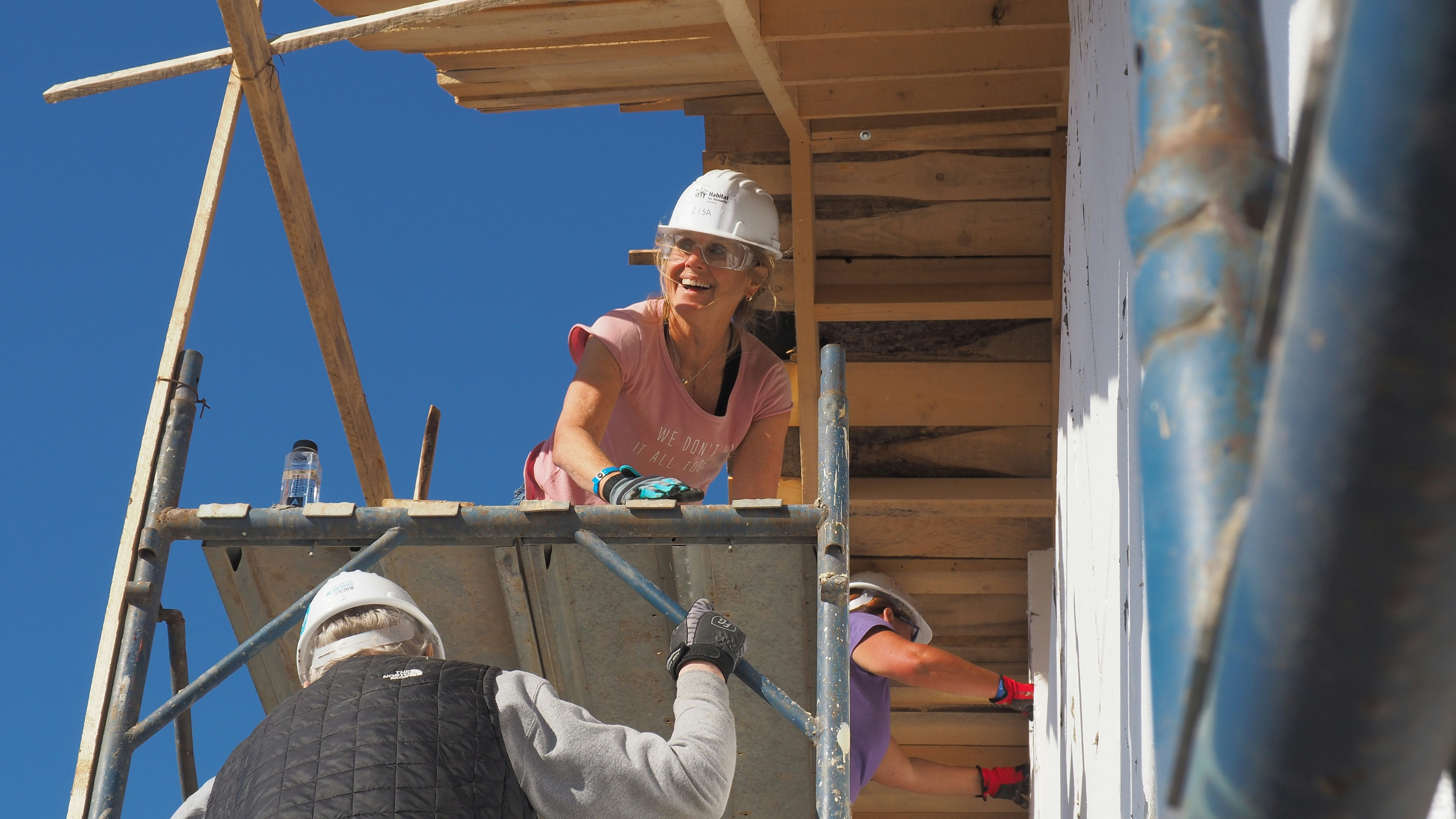Volunteers working together on a nonprofit construction project while wearing safety gear.