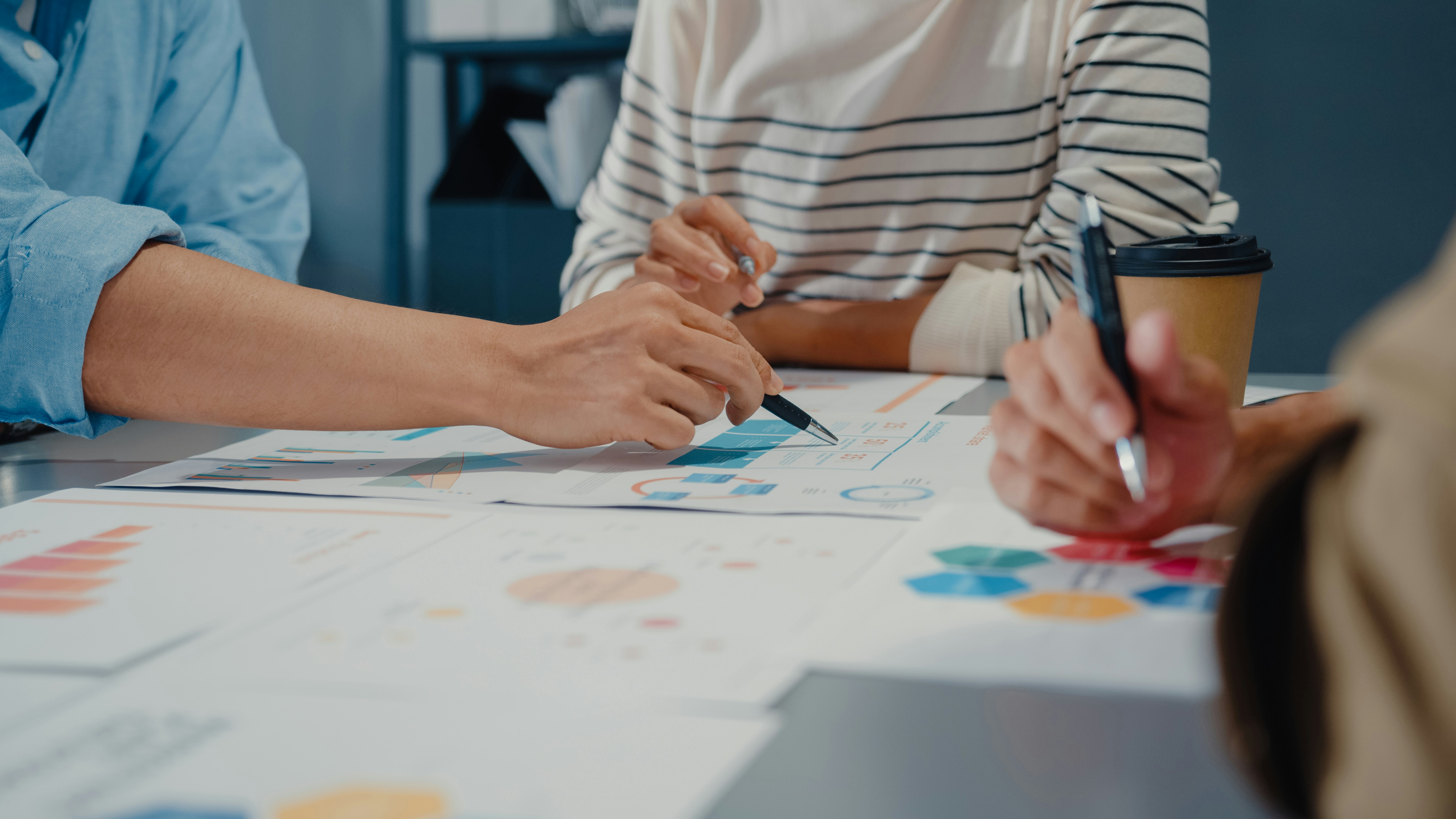 Close-up of multiple people reviewing printed charts and diagrams on a table.
